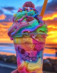 a hand holding up a colorful ice cream sundae