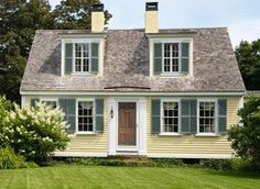 a white house with green grass and trees in the background