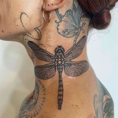 a woman with tattoos on her neck and behind the neck is a dragonfly tattoo