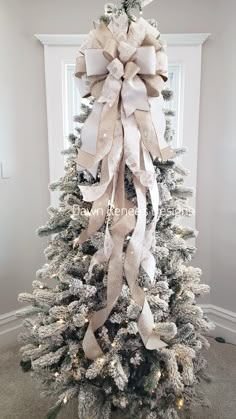 a white christmas tree decorated with bows and lights