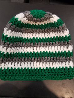 a green and white crocheted beanie sitting on top of a black table