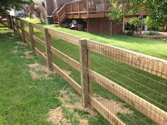 a wooden fence in front of a house with grass on the ground and stairs leading up to it