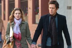 the man and woman are walking down the street holding hands with each other while wearing scarves