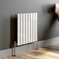 a white radiator in the corner of a room with wood floors and gray walls