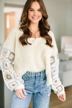 a smiling woman wearing jeans and a sweater