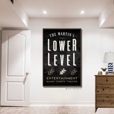 a poster on the wall above a dresser in a room with white walls and wood floors