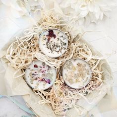 three small bowls filled with food sitting on top of a wooden tray next to flowers