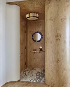 a bathroom with wood paneling and a round mirror on the wall next to it