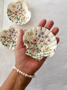 a hand holding two small plates with flowers on them