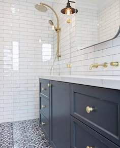 a bathroom with blue cabinets and white tile on the floor, along with a gold faucet