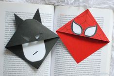 an open book with two origami animals on it, one is red and the other is black