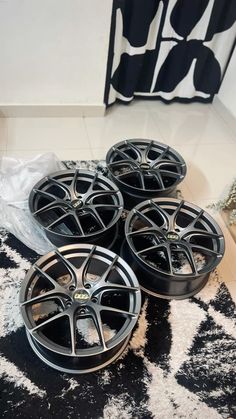 four black rims are sitting on the floor next to each other in front of a rug