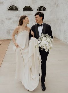 a man in a tuxedo and a woman in a wedding dress walking together