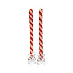 two red and white striped candles sitting next to each other on top of glass holders