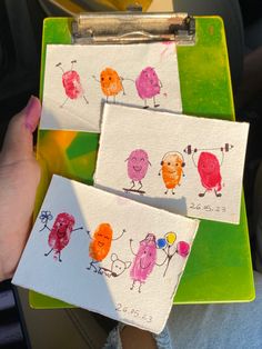 three little cards with different designs on them in someone's hand, one is holding a clipboard