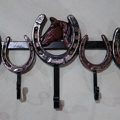 three metal horseshoes mounted to the side of a wall with horse heads on them