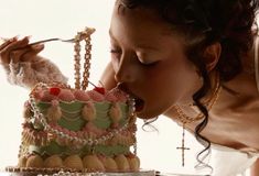 a woman is eating from a cake with pearls on it