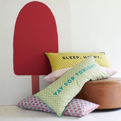 three pillows and a wooden stool in front of a wall