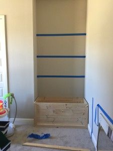 an empty room with some blue tape on the wall and a wooden box in the corner