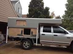 a silver truck with a camper attached to it's bed parked in front of a house