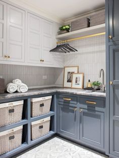 a kitchen with gray cabinets and white walls, baskets on the counter top and shelves above it