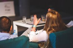 two people sitting in chairs with their hands up