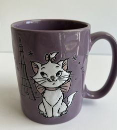 a purple coffee mug with an image of a cat and the eiffel tower