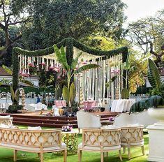 an outdoor wedding setup with white chairs and greenery