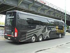 a black tour bus parked under a bridge