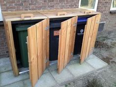 three wooden doors open in front of a brick building with trash cans and bins