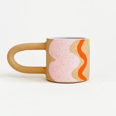 a pink and orange coffee cup sitting on top of a white table