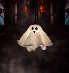 a ghost lamp hanging from a string in front of a dark room with stained glass windows