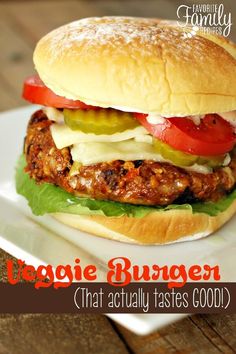 a chicken burger with lettuce, tomato and cheese on it sitting on a white plate