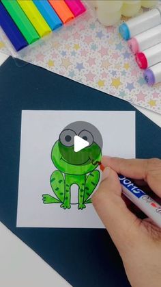 someone is drawing a cartoon frog on paper