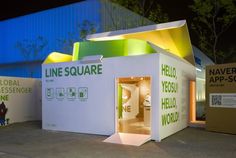 a small white building with green and yellow lettering on it's side at night