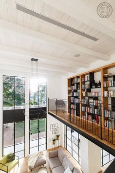 a living room filled with furniture and bookshelves next to a large open window