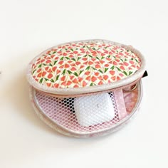 an orange and white flowered cosmetic bag sitting on top of a table