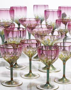 many pink wine glasses are lined up on the table with one empty glass in front of them