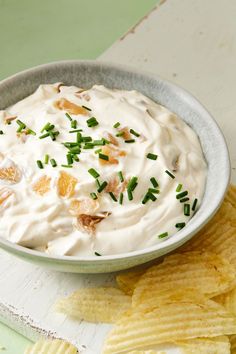 a bowl filled with white dip surrounded by chips