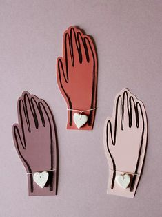 three hand shaped magnets with hearts attached to them