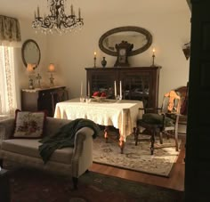 a living room filled with furniture and a chandelier hanging from the ceiling over a table