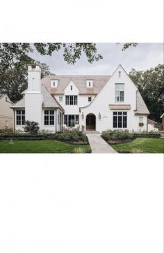 a large white house sitting on top of a lush green field