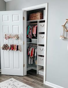 an open closet with clothes hanging on the door and other items in baskets next to it