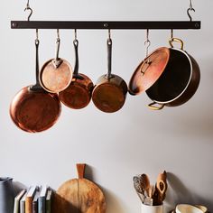 pots and pans hanging from hooks on a wall