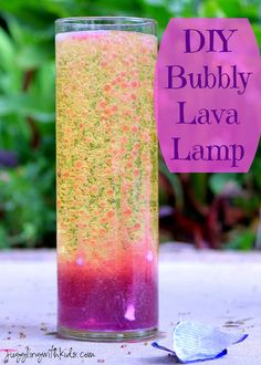 a glass filled with liquid sitting on top of a table next to a spoon and green plants