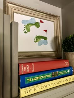 books are stacked on top of each other in front of a framed golf player's foot print