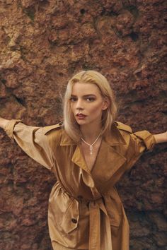 a woman standing in front of a rock wall with her arms outstretched out to the side