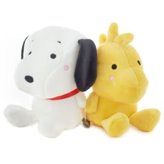 two stuffed animals sitting next to each other on a white surface with one dog holding the other's head