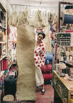 a woman standing next to a large piece of jute in a store filled with lots of items