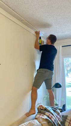 a man is painting the wall in his bedroom with white paint and a yellow sprayer